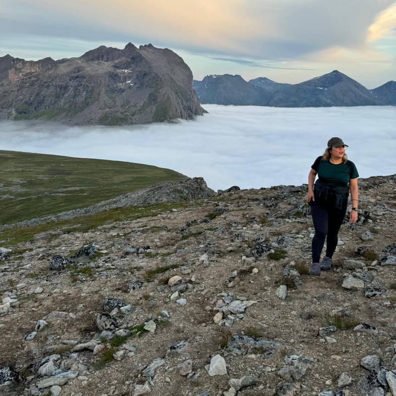 Afsheen hiking Brosmetinden on Kvaløya island near Tromsø, Norway, above the clouds under the midnight sun
