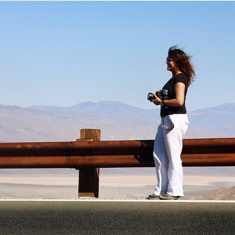 Afsheen holding her camera beside a road overlooking Death Valley, California